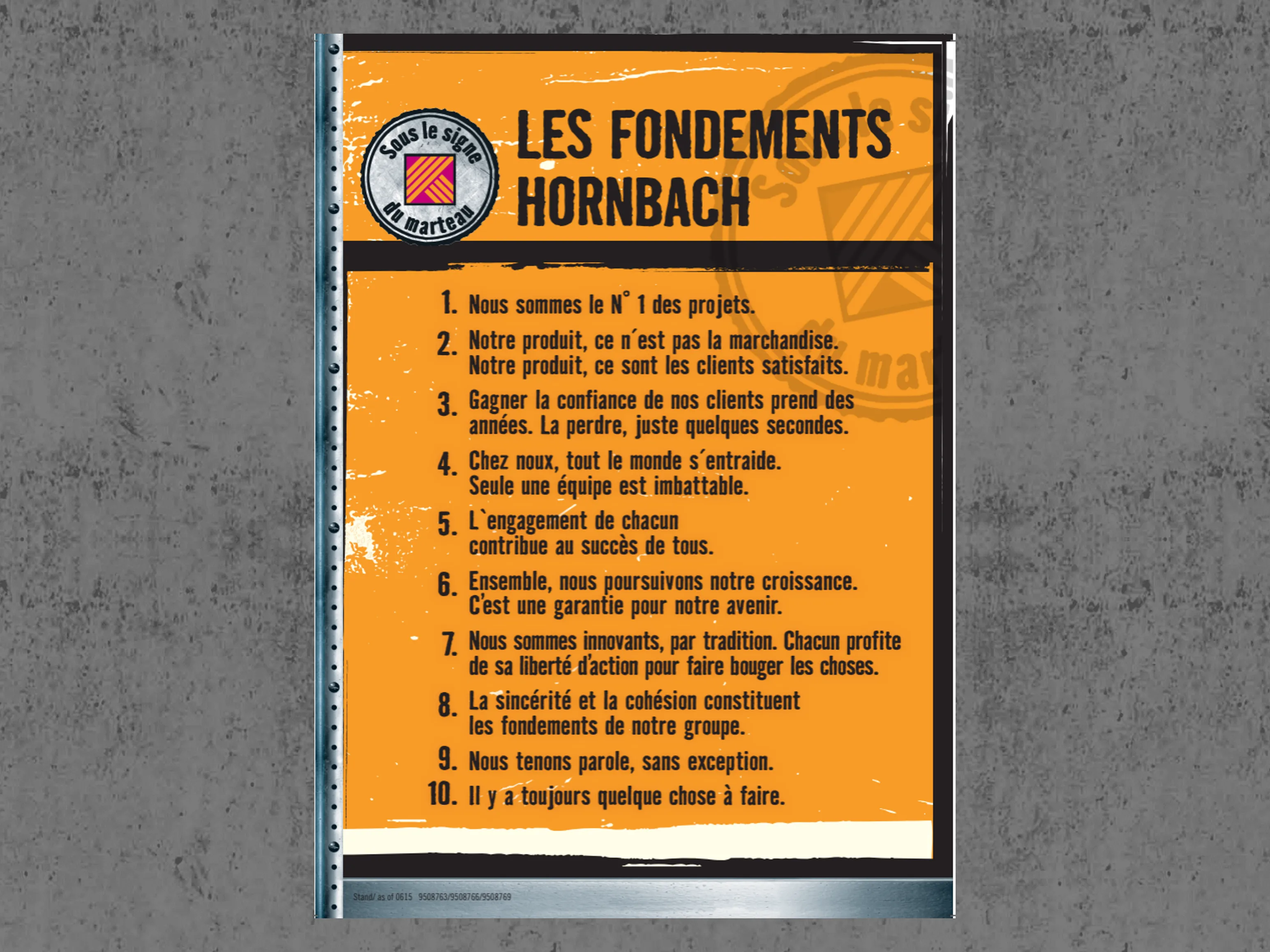 Affiche orange avec les "Fondements HORNBACH", énumérant dix principes de l'entreprise sous le signe du marteau.