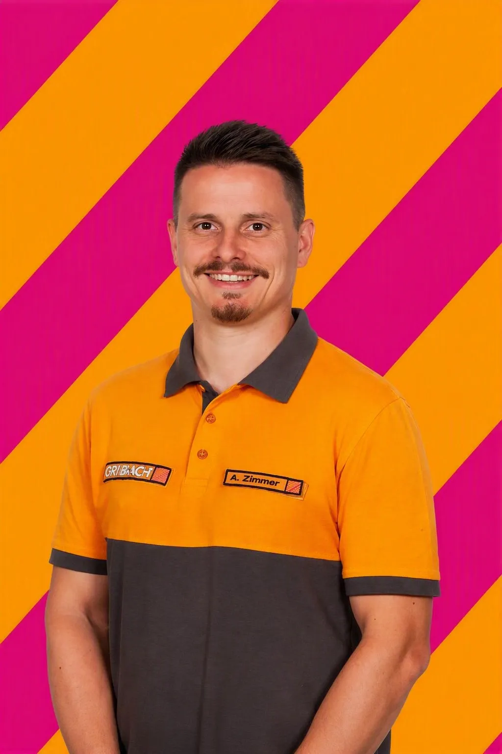 Der lächelnde Mitarbeiter Andreas Zimmer von HORNBACH in orange-grauer Arbeitskleidung vor einem bunten Hintergrund.
