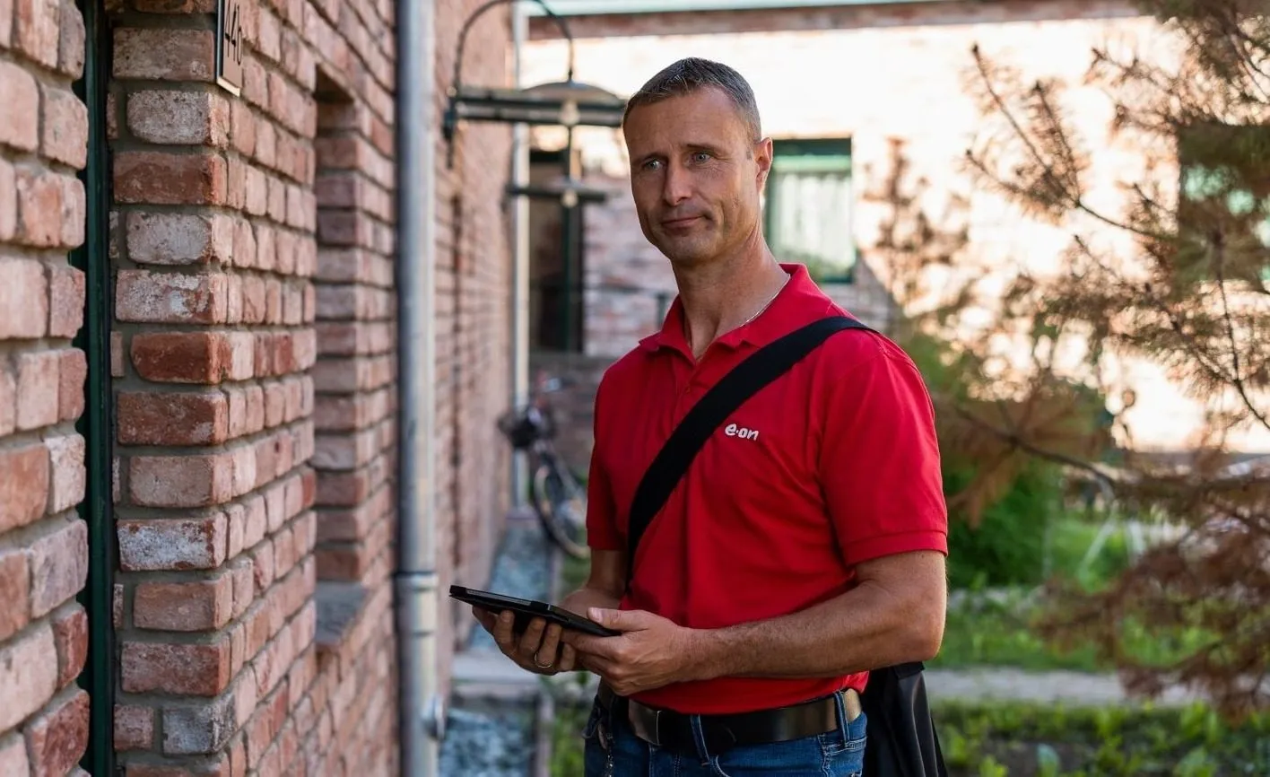 Mann mit roten Shirt und iPad vor Haus