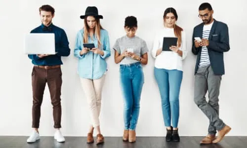 Fünf junge Menschen stehen mit digitalen Geräten und arbeiten zusammen – starte Deine Karriere bei impeak im Consulting.