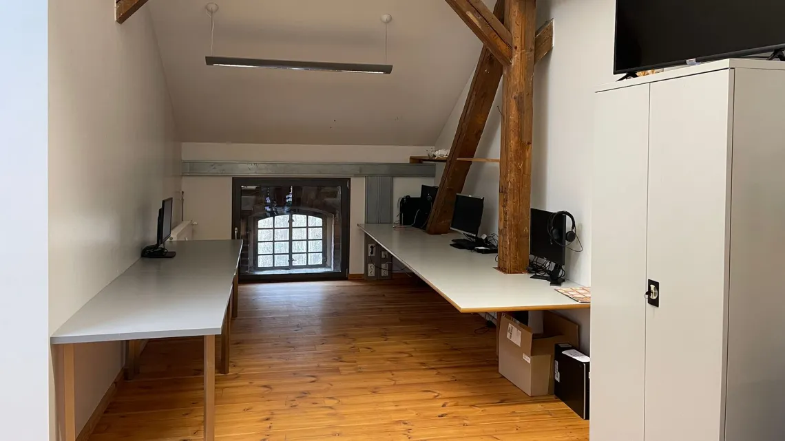 Heller Büroraum mit modernen Arbeitsplätzen und Holzbalken, in dem Du bei impeak GmbH als Consultant arbeiten kannst.
