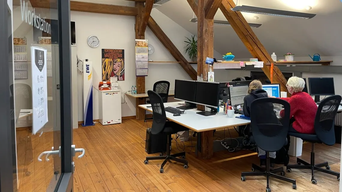 Modernes Büro mit Holzdetails, in dem zwei Kolleginnen gemeinsam am Computer arbeiten – hier kannst Du im Team durchstarten.
