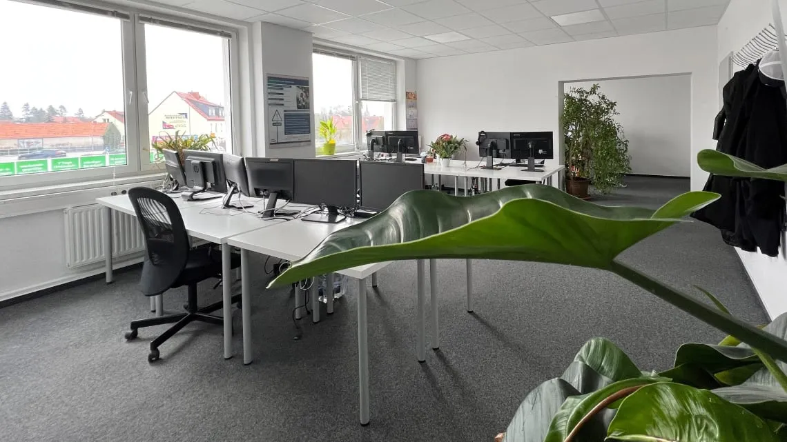 Modernes, helles Büro bei impeak GmbH mit mehreren Arbeitsplätzen, großen Fenstern und vielen Pflanzen. Hier kannst Du arbeiten.