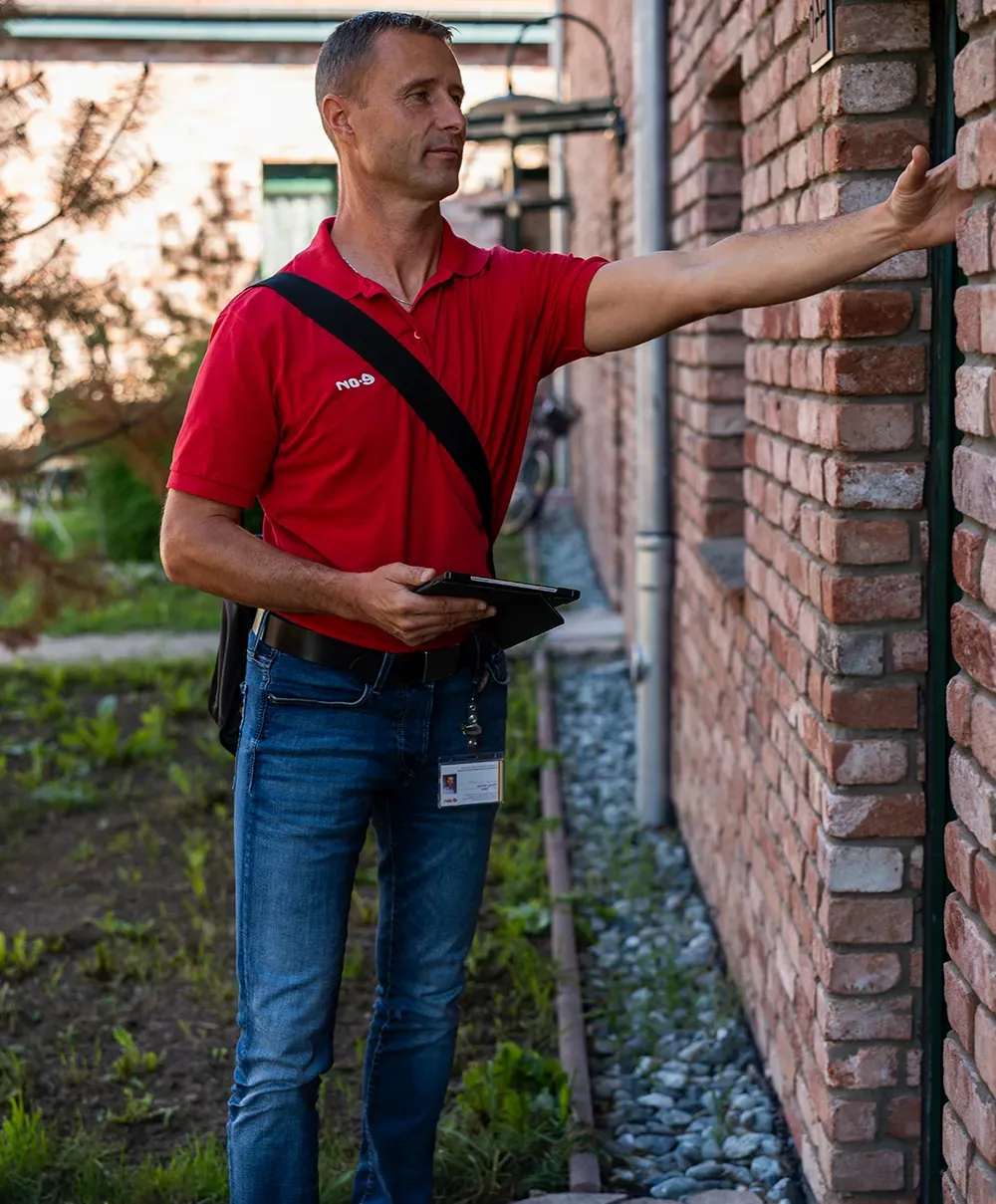 Eine Person im Mantel hält einen E.ON-Regenschirm und öffnet die Tür eines Hauses.
