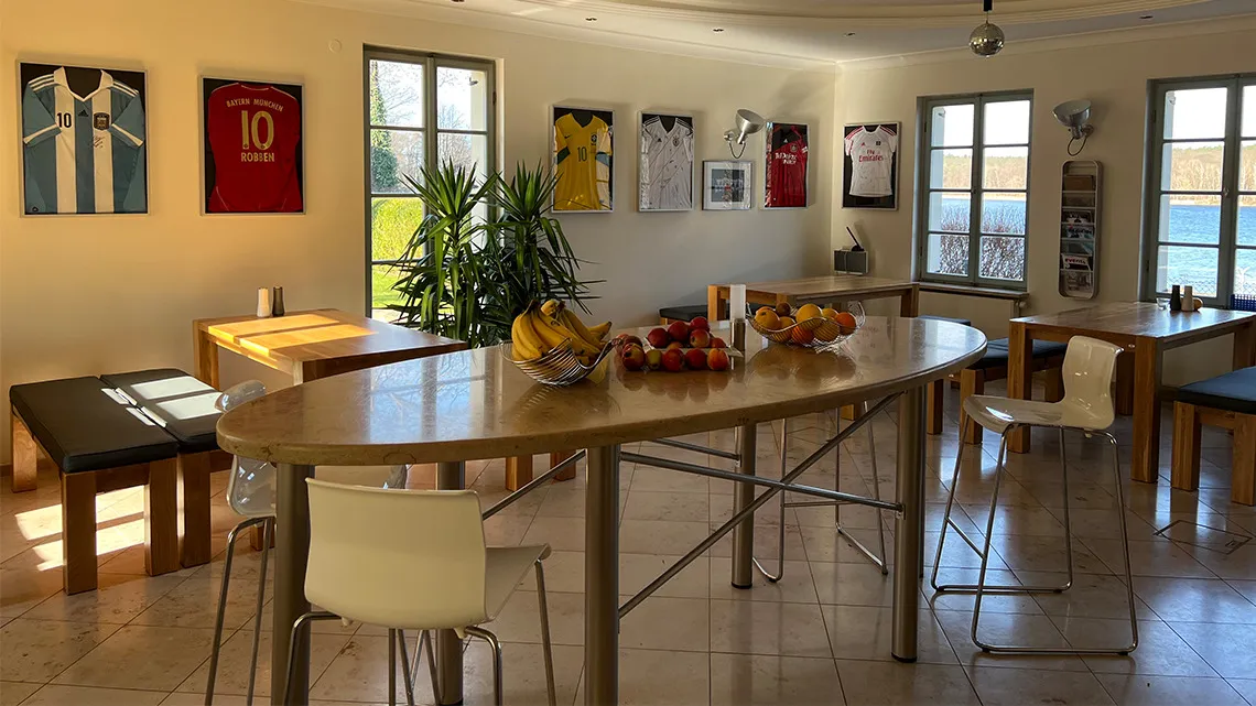 Heller Pausenraum mit Obst, modernen Sitzgelegenheiten und Fußballtrikots an der Wand bei impeak GmbH.