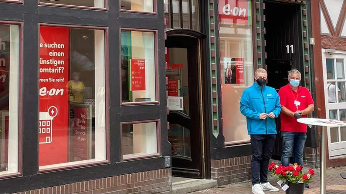 Zwei Berater stehen vor einem E.ON-Büro, bereit, Dich freundlich zum Beratungsgespräch zu empfangen.