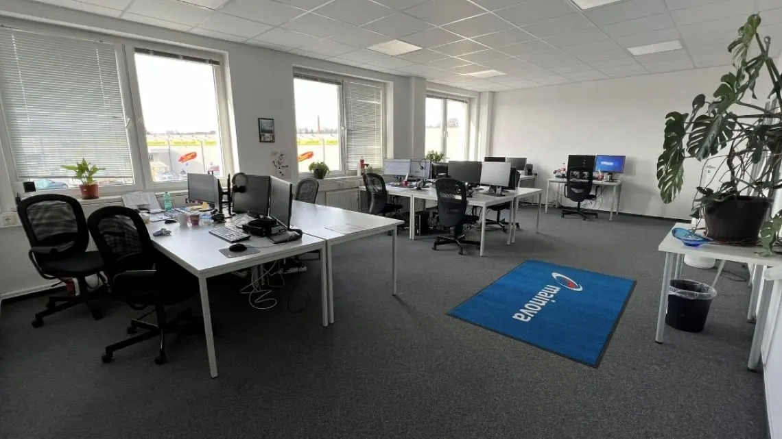 Helles, modernes Großraumbüro mit mehreren Arbeitsplätzen, Pflanzen und Computern bei impeak GmbH.