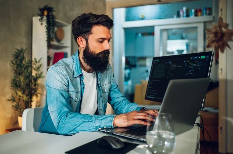 Du arbeitest fokussiert im Homeoffice an einem Laptop mit Finanzdaten auf dem Bildschirm.