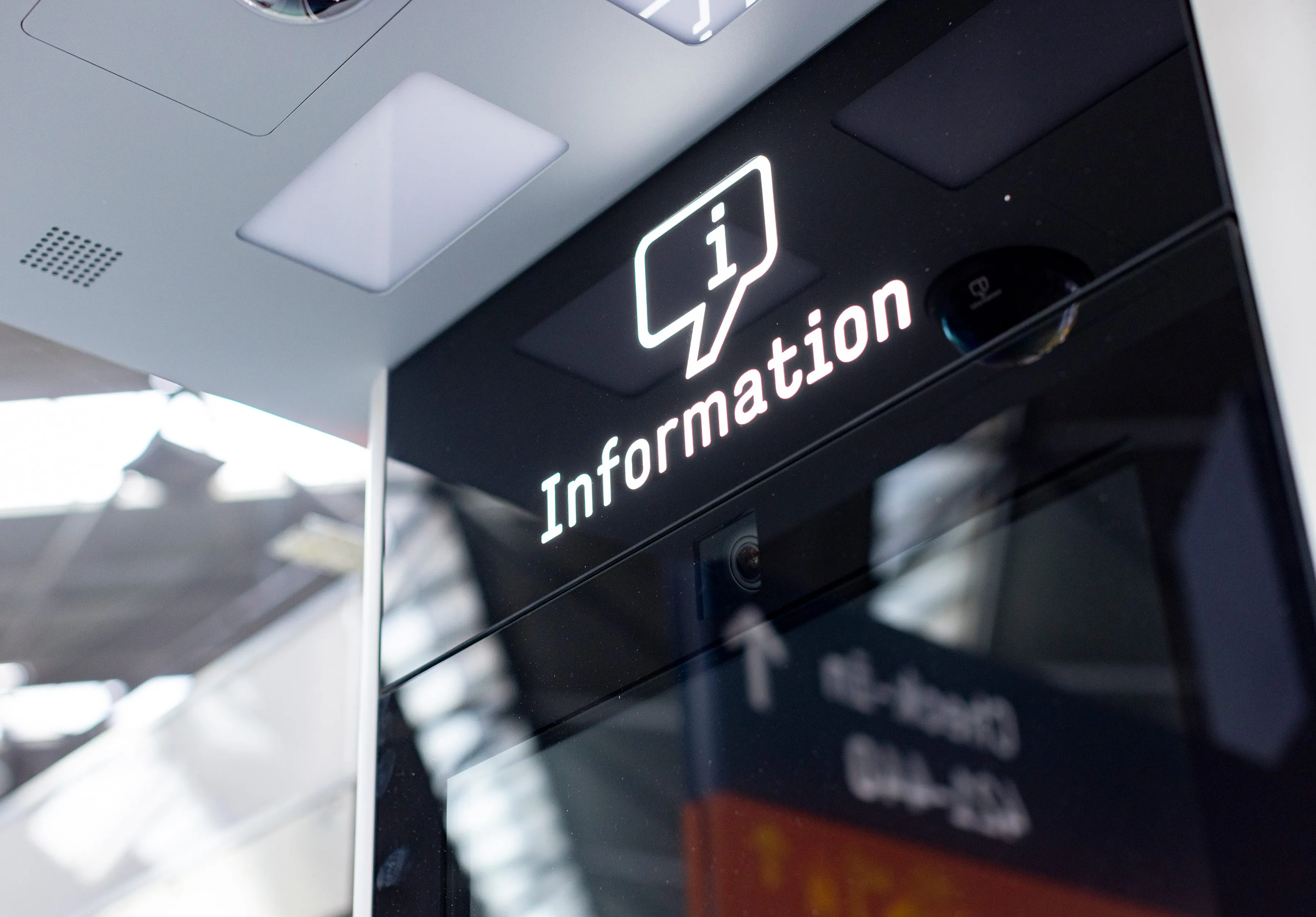 Ein digitales Informationsschild mit einem "i"-Symbol und der Aufschrift "Information" in einem modernen, hellen Raum.
