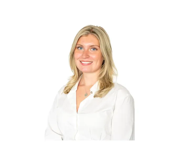 Junge Frau mit blondem Haar im Business-Outfit lächelt freundlich vor dunklem Hintergrund für dein Karriereprofil.