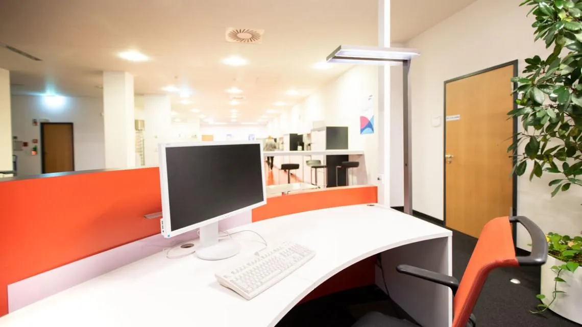Moderner Arbeitsplatz mit Computer und ergonomischem Stuhl in einem hellen Büro bei KVM ServicePlus im Versicherungsbereich.