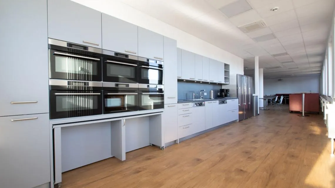 Moderne, helle Büroküche mit mehreren Mikrowellen, Kühlschrank und Sitzbereich für Deine Pausen bei KVM ServicePlus.