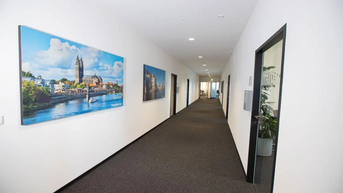 Heller Büroflur bei KVM ServicePlus mit modernen Bürotüren und Bildern von Magdeburg an der Wand.