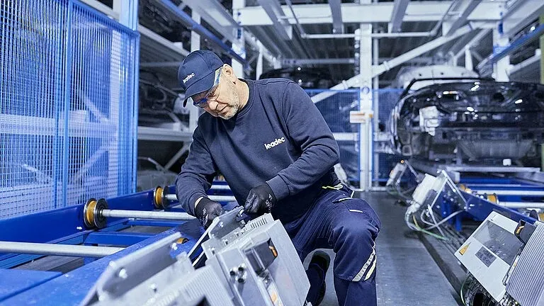 Ein Leadec-Mitarbeiter arbeitet konzentriert an einer Maschine in einer modernen Produktionshalle.