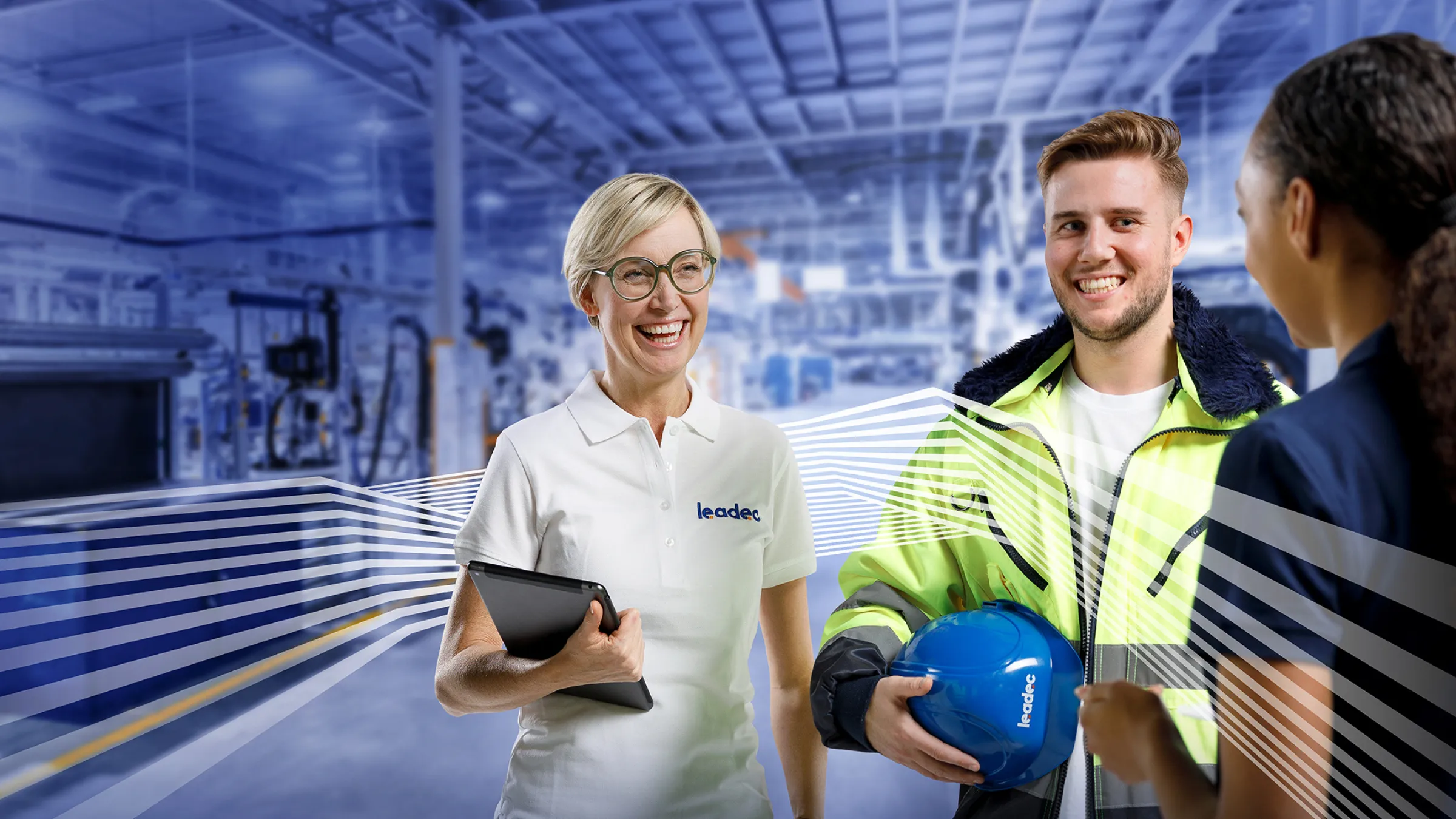 Drei Leadec-Mitarbeitende lächeln und unterhalten sich in moderner Industrieumgebung, du stehst im Mittelpunkt des Teams.