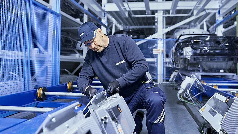 Ein Leadec-Mitarbeiter wartet eine Maschine in einer modernen Produktionshalle der Automobilindustrie.