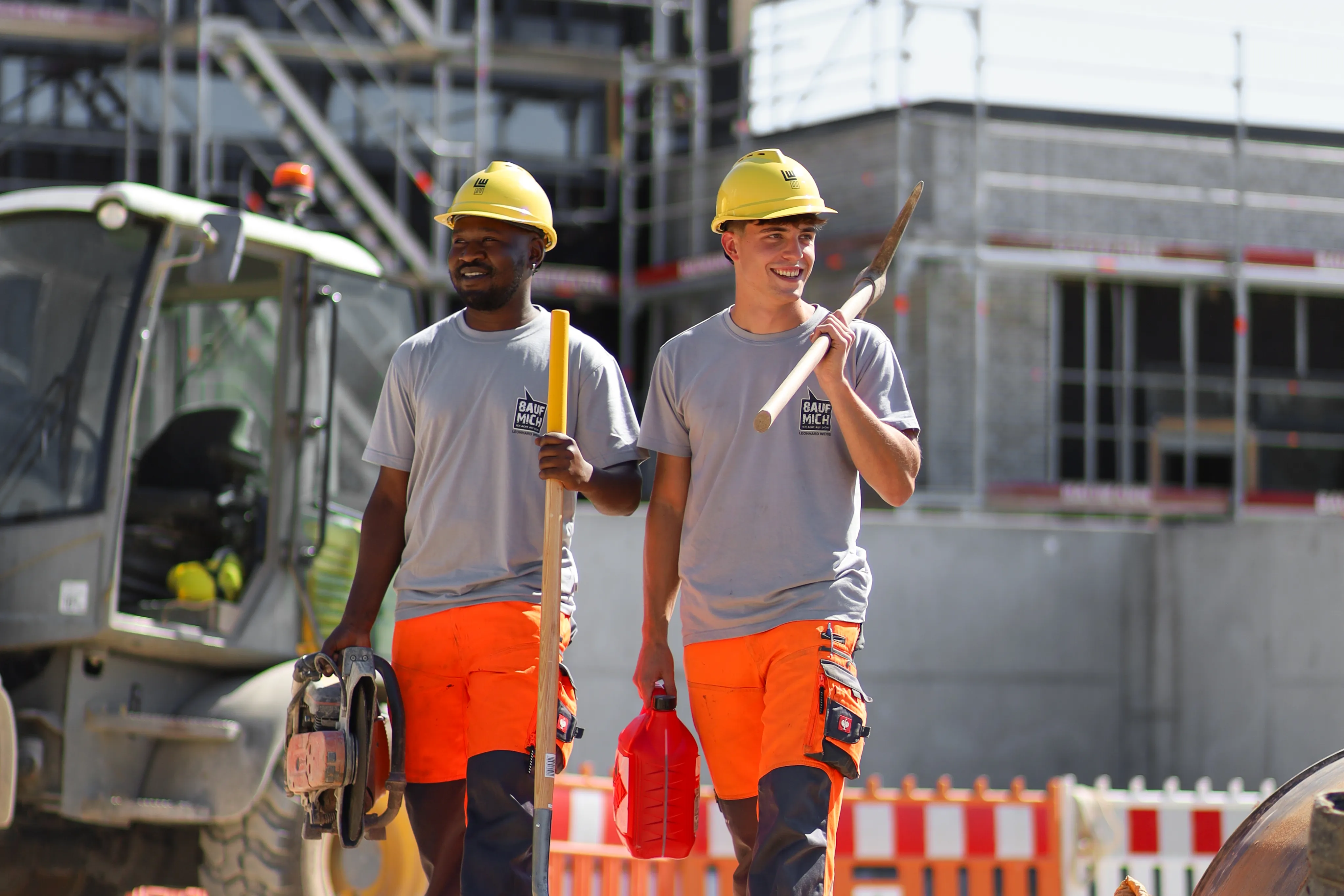 Zwei Leonhard-Weiss-Baumaschinen im Einsatz auf einer Baustelle, umgeben von Bäumen und Gebäuden.