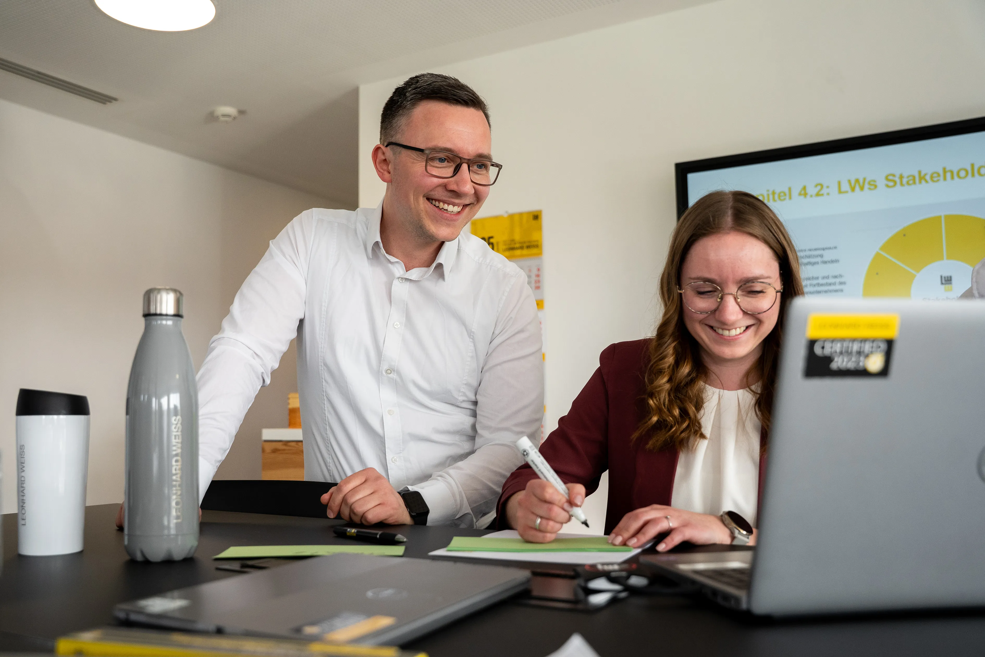 Drei Bauingenieure besprechen Projekte an einem Tisch mit Laptop und Tablet bei Leonhard Weiss GmbH & Co. KG.