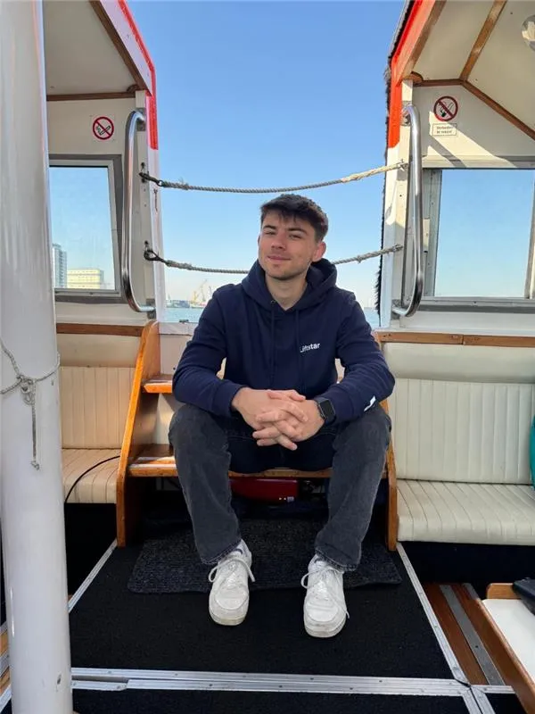 Junger Mann im Liftstar-Pullover sitzt entspannt auf einem Boot. Duales Studium Köln-Marsdorf.