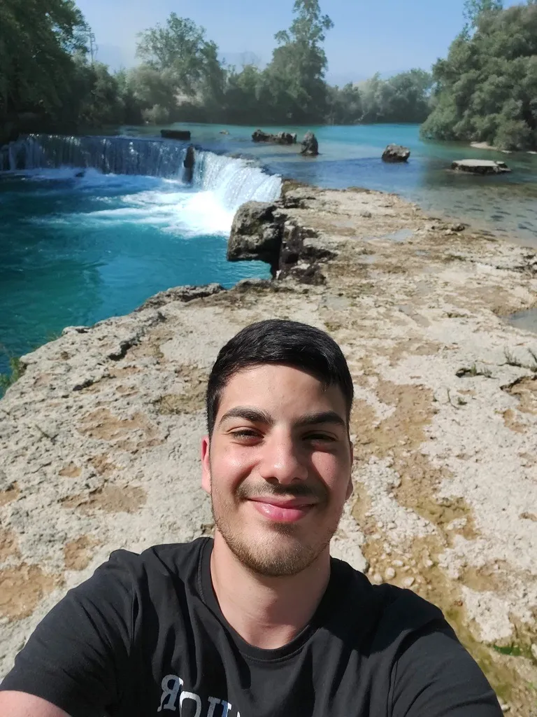 Junger Mann macht ein Selfie vor einem Wasserfall in der Natur – entdecke bei Liftstar Deine Work-Life-Balance im Gesundheitsbereich.