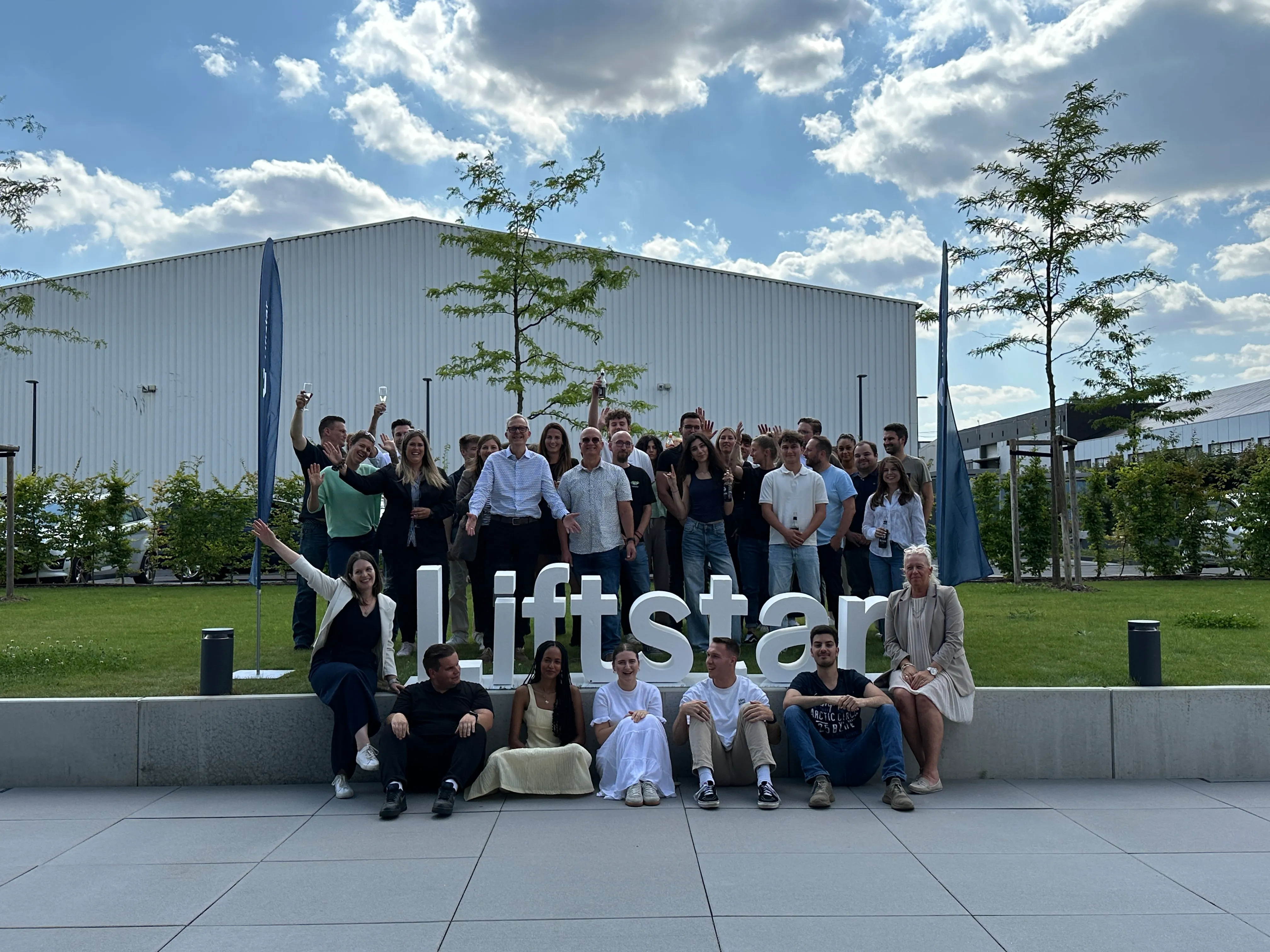 Gruppenfoto des Liftstar-Teams fröhlich vor dem Firmenlogo im Freien – werde Teil unseres Healthcare-Teams!