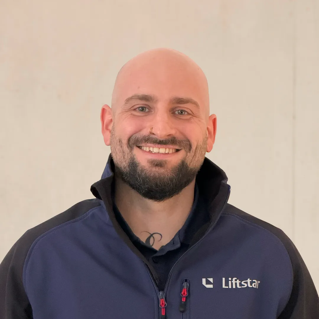 Ein freundlich lächelnder Mitarbeiter von Liftstar in Arbeitskleidung, bereit für Deinen Einstieg im Gesundheitsbereich.