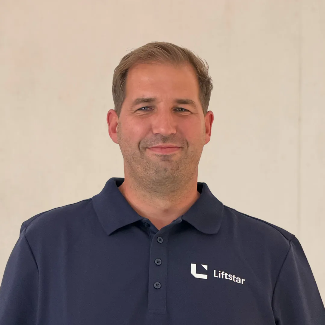 Mitarbeiter von Liftstar GmbH lächelt in Firmenkleidung vor neutralem Hintergrund – werde Teil unseres Healthcare-Teams.