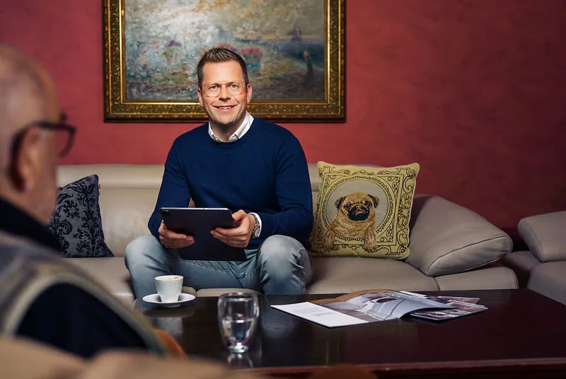 Ein Mann sitzt mit Tablet und freundlichem Blick auf einem Sofa, bereit für ein Vertriebsgespräch bei Liftstar im Gesundheitsbereich.
