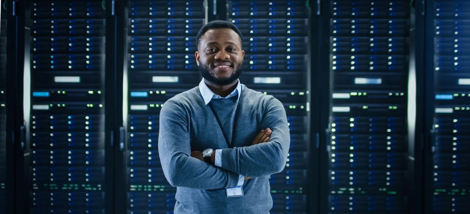 IT-Experte mit verschränkten Armen steht vor Servern und lächelt, bereit für neue Herausforderungen bei Logicalis GmbH.