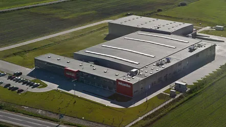 Aerial view of a Miele manufacturing facility in Brasov surrounded by green fields, showcasing its modern design and expansive layout.