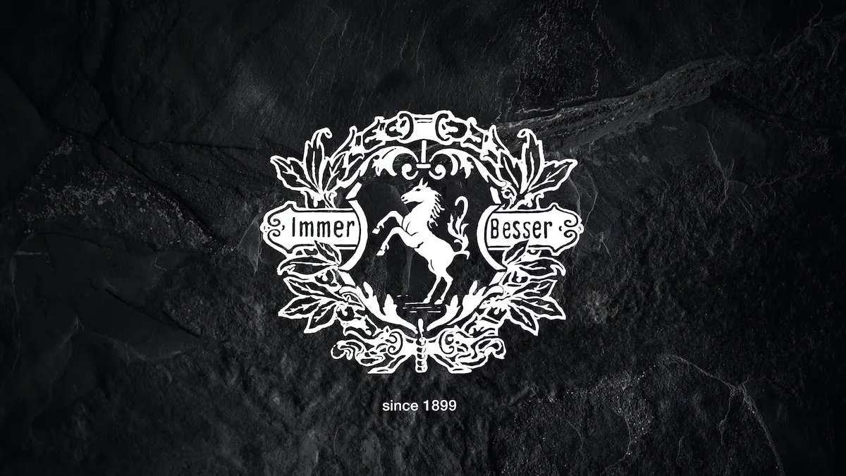 Weißes Miele Logo mit dem Schriftzug Immer Besser und einem Pferd in der Mitte auf einem schwarzen Hintergrund