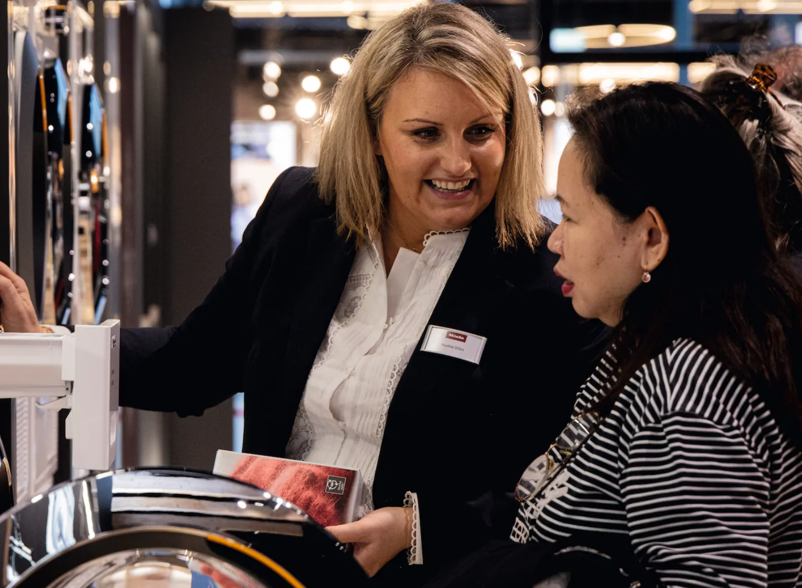 Chef in a Miele uniform plating a gourmet dish with fresh vegetables in a stylish kitchen setting.