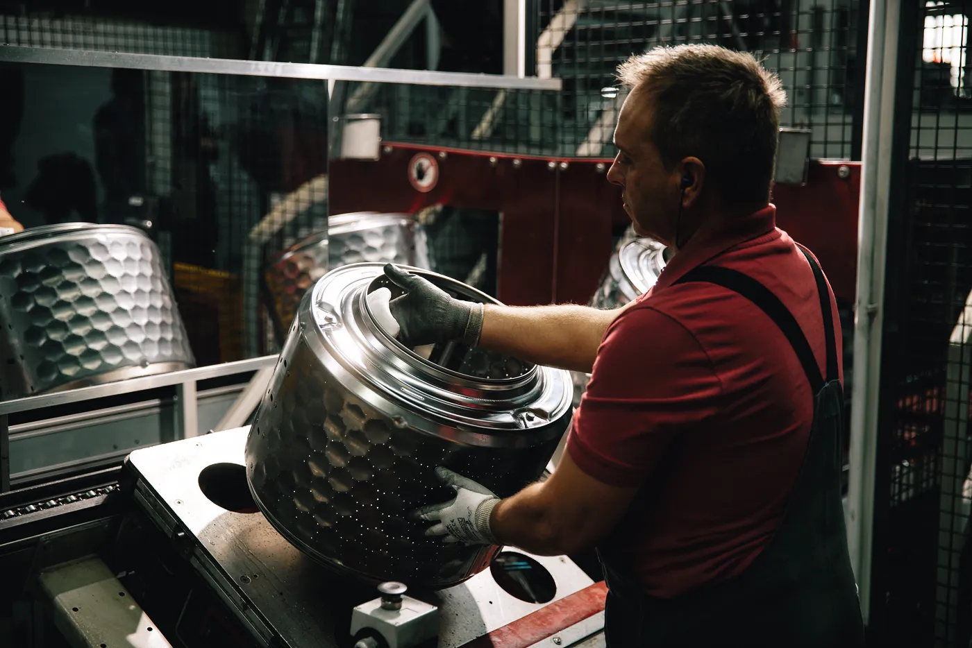 Ein Mitarbeiter bei Miele montiert eine Waschmaschinentrommel in der Fertigungshalle.