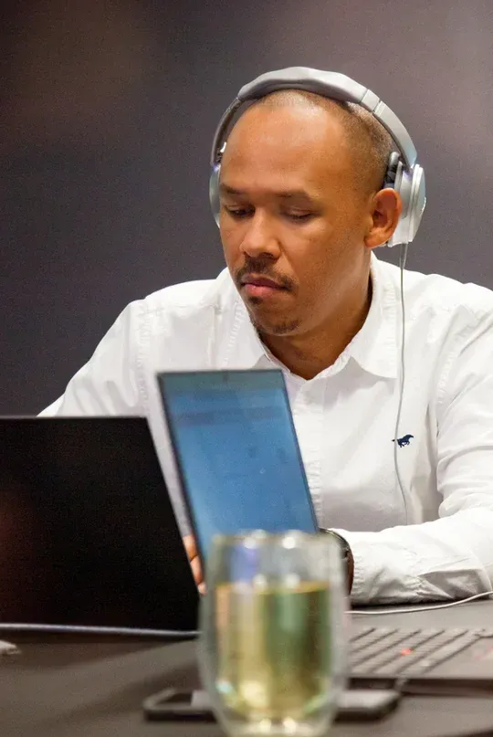 Person wearing headphones, focused on work at a laptop, embodying Miele's innovative spirit.