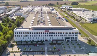 Aerial view of Miele & Cie. KG's modern manufacturing facility in Unicov, surrounded by green fields and parking area.