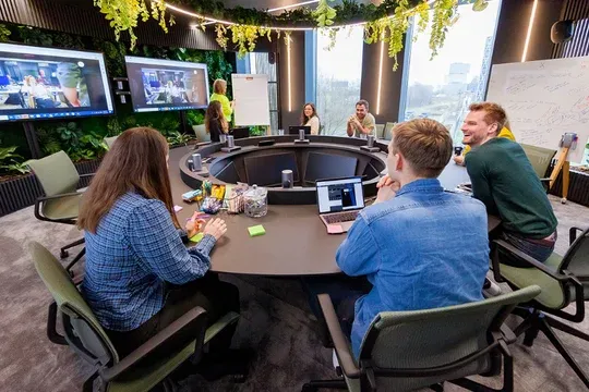 Team brainstorming session in a modern conference room with video screens at Miele, featuring snacks and lively discussion.