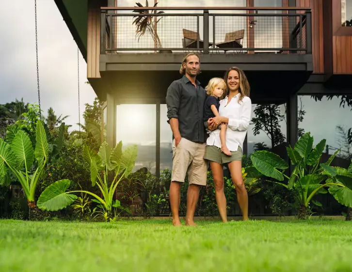 Family standing outside a modern home surrounded by greenery, highlighting Miele's commitment to sustainability.