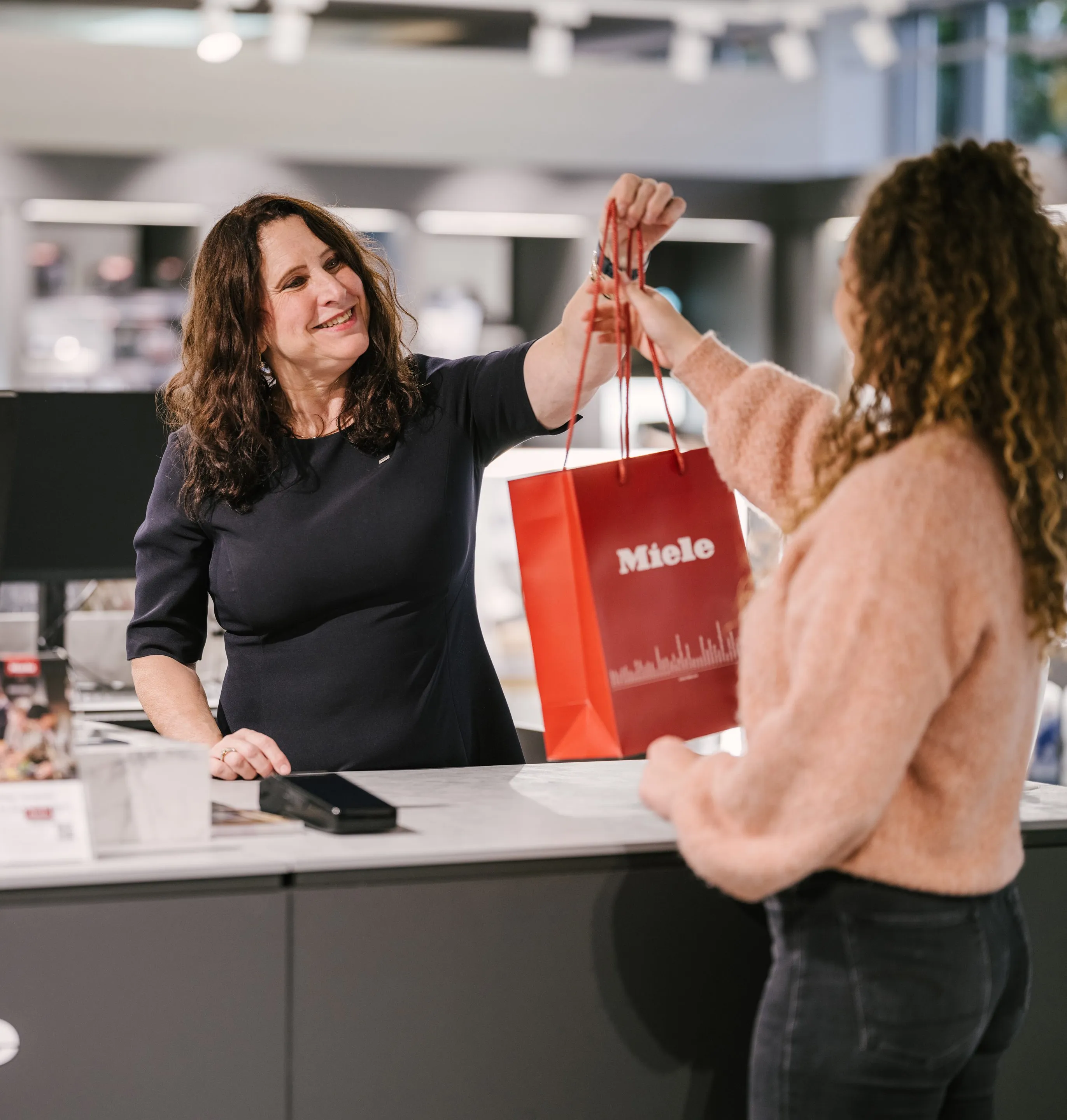 Three business professionals walking and talking inside a modern office building at Miele & Cie. KG.