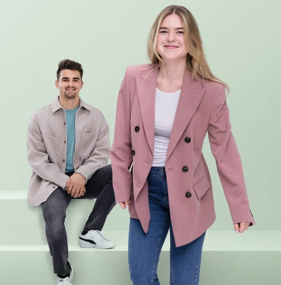 Zwei junge Erwachsene in moderner Kleidung lächeln in die Kamera, ideal für die Karriere-Website von Miele & Cie. KG.