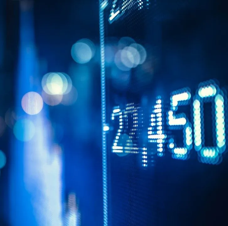 A confident woman in a black top stands smiling in front of design posters, embodying Miele’s innovative spirit.