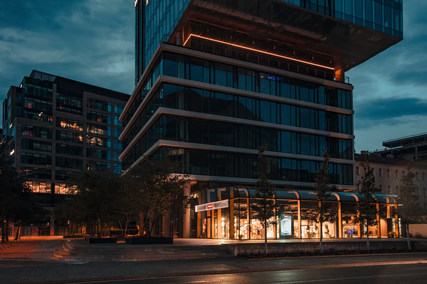 Moderní budova Miele večer osvětlená, ideální místo pro kariéru v oboru výroby.