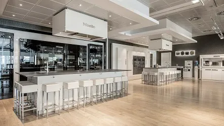Modern Miele kitchen showroom in Spain with sleek appliances, spacious counters, and stylish seating in a bright, open space.