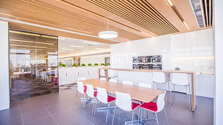 Moderne Büroküche bei Miele in China mit Holzdecke, Esstisch und weißen Stühlen, ideal für Mitarbeitertreffen.