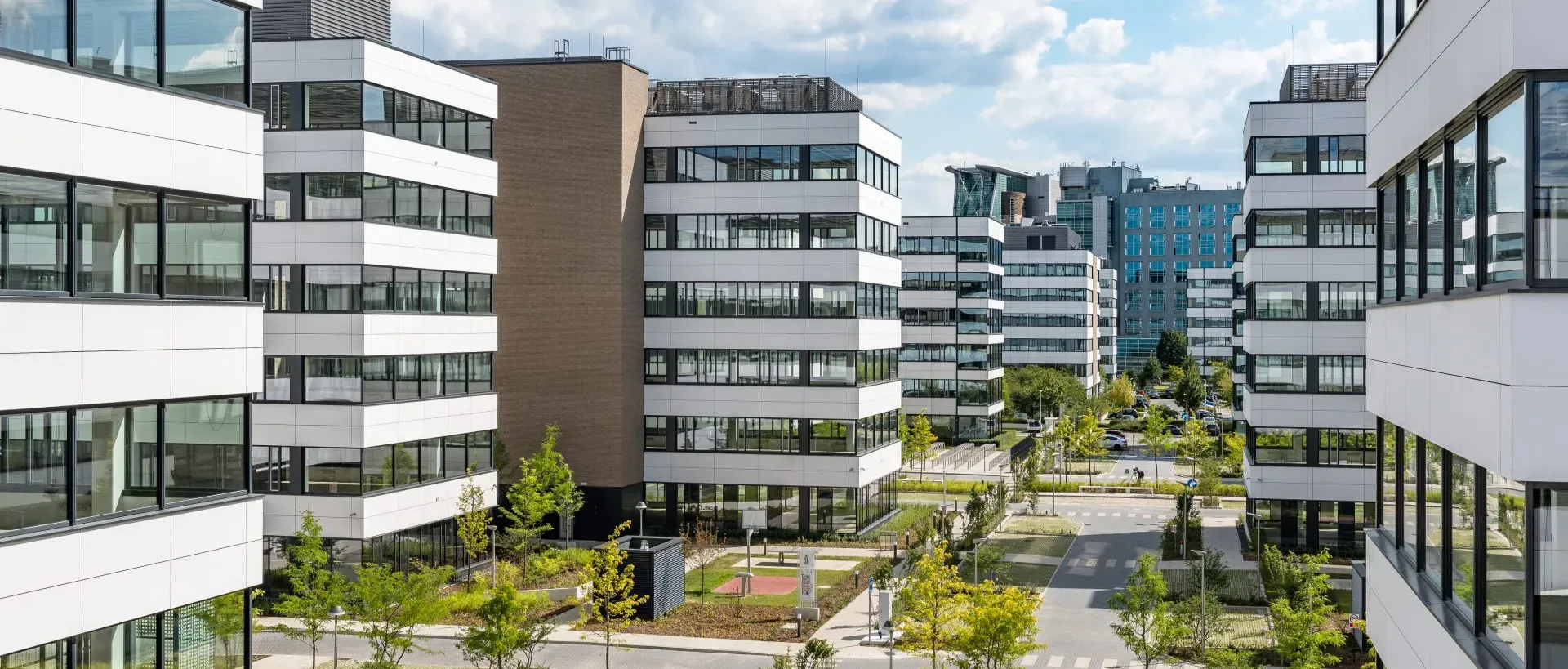 Modern office buildings of Miele Global Services with green pathways and a vibrant urban vibe.