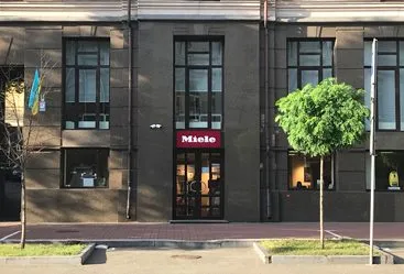 Front view of a Miele office building in Ukraine with large windows and a welcoming entrance, showcasing a modern industrial vibe.