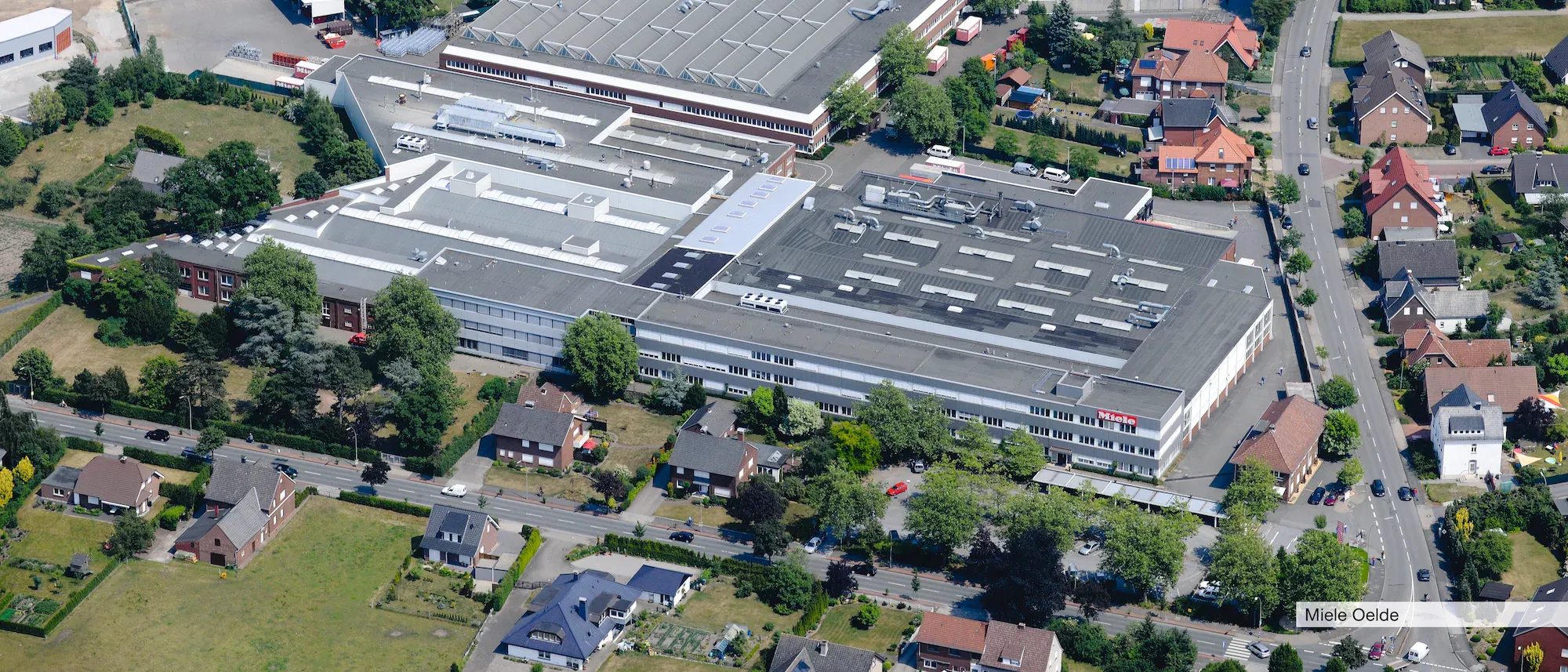 Luftaufnahme des Miele-Werks in Oelde, umgeben von Wohnhäusern und grünen Flächen.