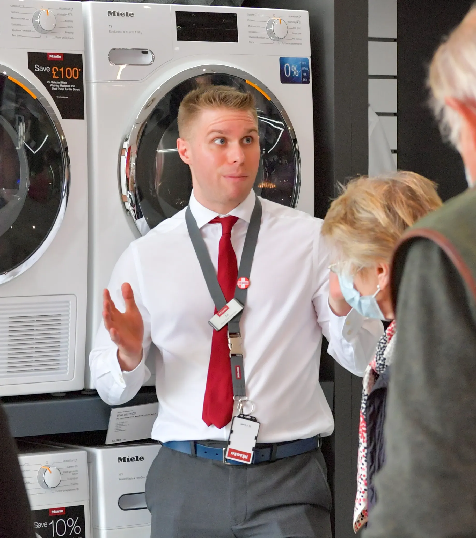 Ed- the Flagship Store Manager enthusiastically explaining washing machines to customers in a showroom.