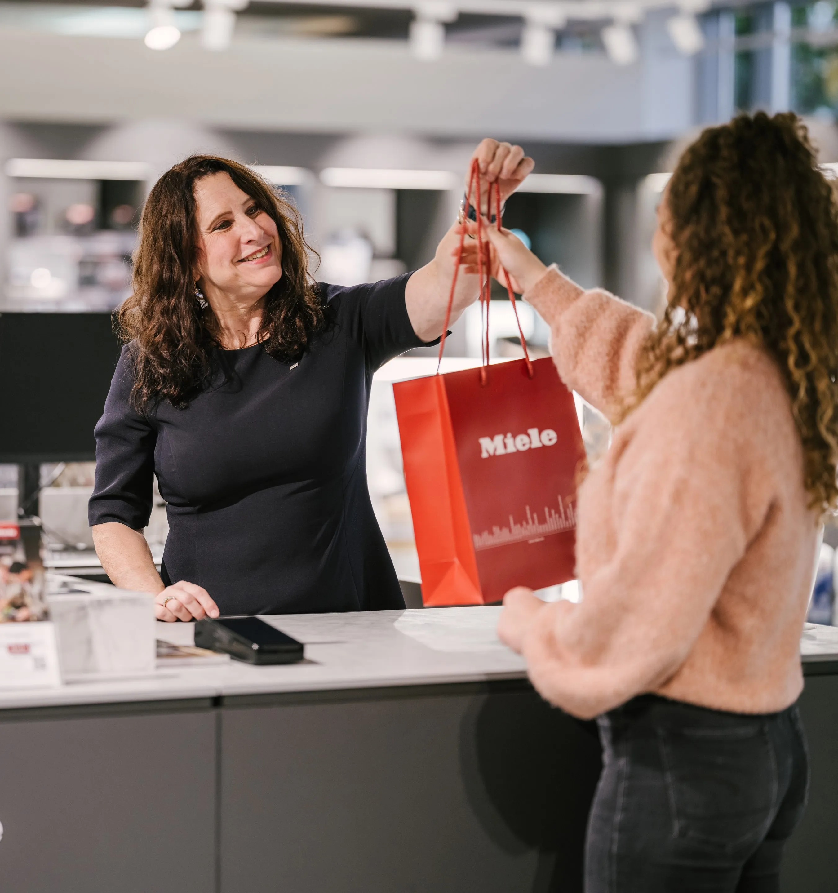 Three business professionals walking and talking inside a modern office building at Miele & Cie. KG.