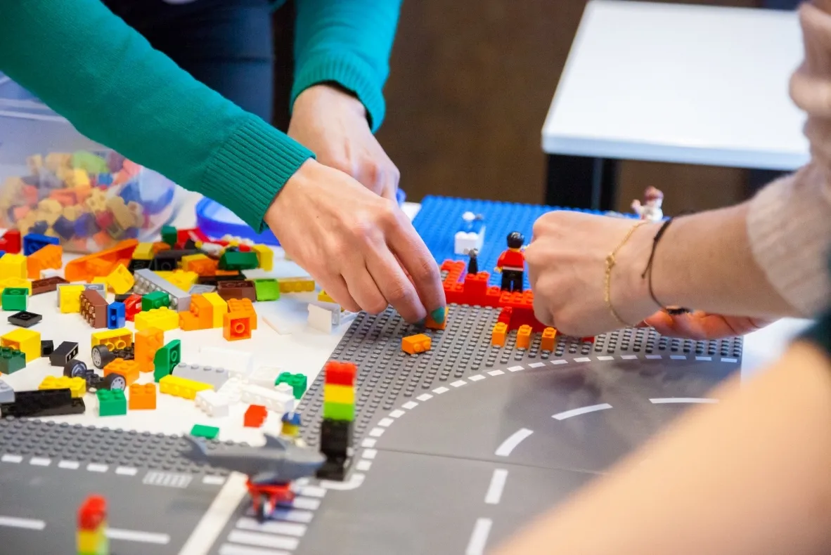 Team members having fun building creative structures with colorful Lego bricks during a hands-on workshop.