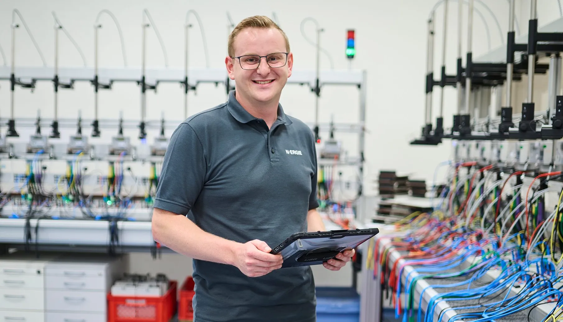 Ein Mitarbeiter von N-ERGIE arbeitet mit einem Tablet im modernen Technikraum voller Messgeräte und Kabel.